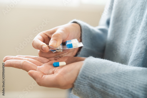 Foto Sick asian young woman, girl taking tablet pill capsule out from blister pack, painkiller medicine for stomach pain, head ache, pain for treatment, take drug or vitamin at home, health care concept