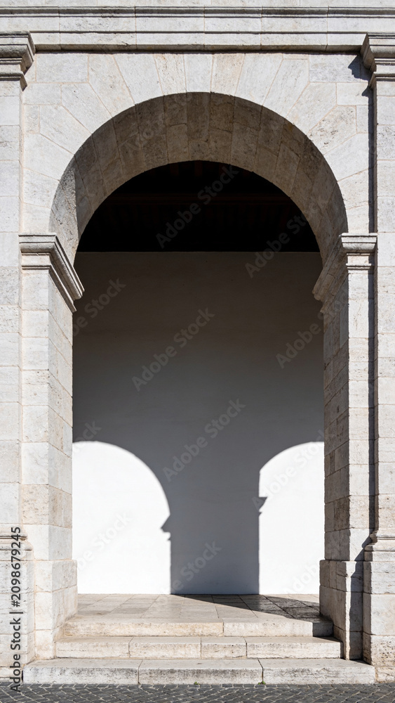 Fototapeta premium Classical stone arches and columns forming a long symmetrical corridor with beautiful light and shadow patterns