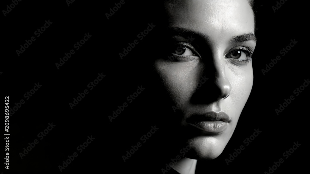 Fototapeta premium Dramatic black and white portrait of a young woman with intense gaze.