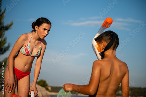Siblings having conflict over snorkeling gear on beach
