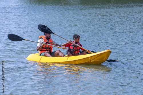 SIGIRIYA, SRI LANKA - JUNE 10, 2026 : A father and son paddle a kayak on Thalkote Lake at Sigiriya in Sri Lanka. In the background stands Sigiriya Rock.