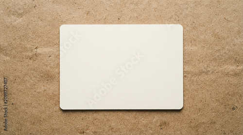 Blank white rectangular card centered on a rustic textured brown recycled paper background surface top view