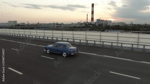 A retro Volga car from the days of the USSR is driving on an overpass in the city