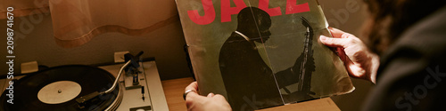 Canvas Print Header of musician holding jazz vinyl record beside turntable at home, exploring music inspiration and analog listening