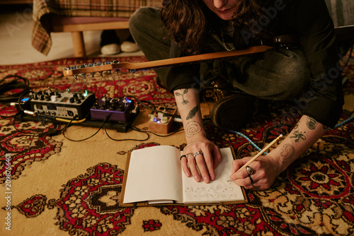 Konstfotografi Cropped shot of male musician writing song lyrics beside electric guitar and effects pedals at home, developing creative process content