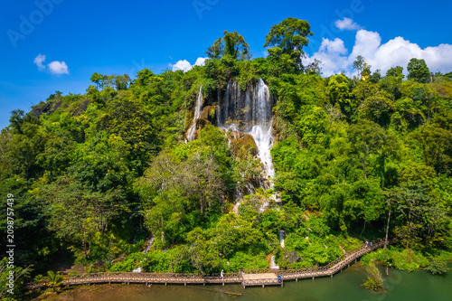 Foto An aerial drone view of the stunning Thararak Waterfall, a beautiful cascade surrounded by lush green forest, a scenic walkway, and a natural pond in Mae Sot, Tak, Thailand
