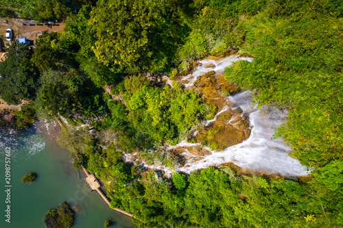 Foto A top view aerial drone shot of the beautiful Thararak Waterfall, showcasing white water cascading down rocky cliffs into a green pond in Mae Sot, Tak, Thailand