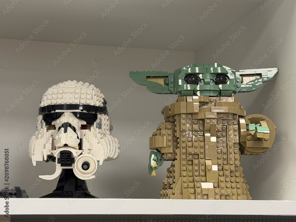Obraz premium Lego star wars stormtrooper helmet and baby yoda figure displayed on a shelf in a home interior.