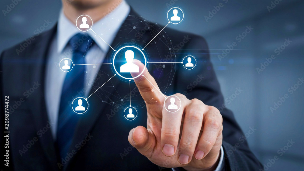 Fototapeta premium Networked Connections: A businessman in a sharp suit touches a glowing interface, connecting various user icons in a digital network. This image symbolizes global connectivity, social networking.