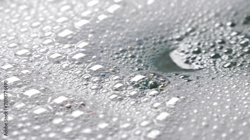 Close-up of white soap suds and water stream creating bubbles