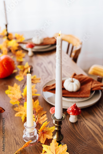 Table set for autumn gathering with candles leaves and seasonal decorations in cozy interior setting