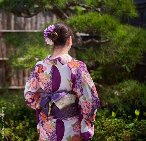 Woman in kimono facing torii gate
