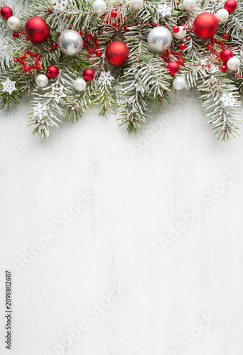 Cuadro en lienzo Snow-covered spruce branches  decorated with Christmas ornaments on old white wooden shabby board with empty space for text