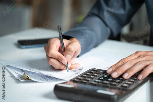 Fotografi Accountant hand using a calculator and writing on financial expense receipt docu