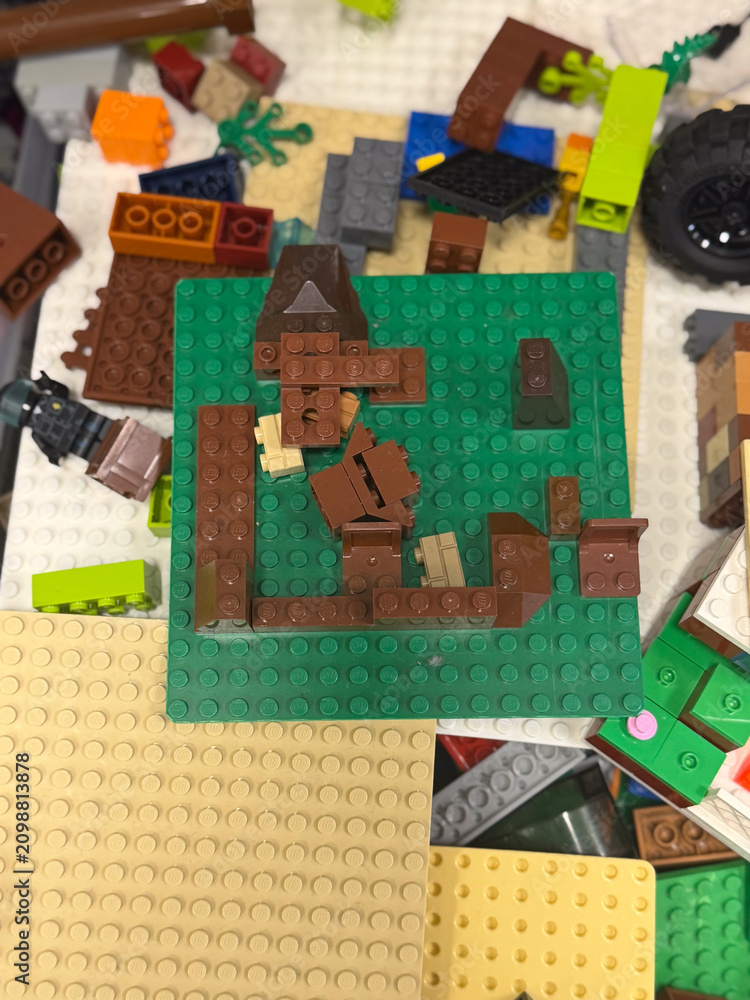 Fototapeta premium Pile of lego bricks and base plates scattered around a green building board