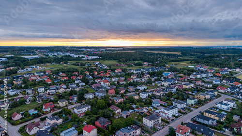 Aerial panoramic view of suburban neighborhood at dramatic sunset under storm clouds
