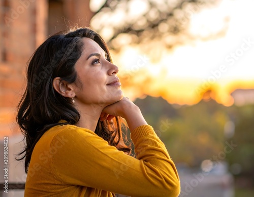 Woman looking up at sunset, calm expression, warm colors