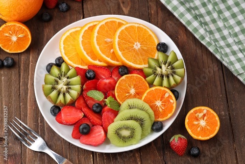 Fresh fruit platter beautifully arranged with a colorful assortment of tropical and seasonal fruits, including kiwi, strawberries, blueberries, and orange slices