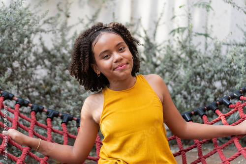 Happy young girl relaxing in a red hammock outdoor