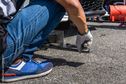 Obraz na płótnie Car mechanic using a manual wheel alignment tool to adjust camber and toe angles