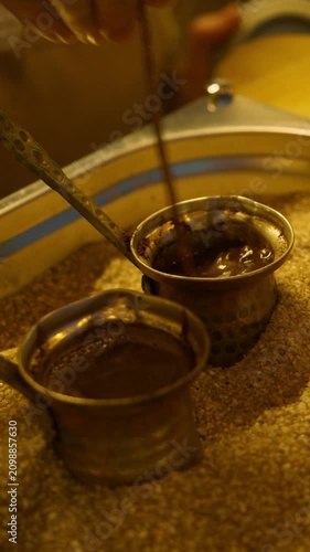 Vendor stirs traditional Turkish coffee in copper pot heated with hot sand. Close up footage captures authentic street coffee preparation with rich aroma.