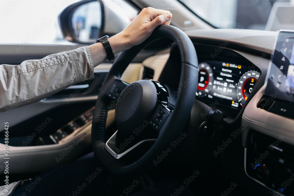 Naklejka premium man driving car. Hands on Steering Wheel Driving a Car. male hands on the steering wheel of a car. Man driving a car at sunset on the seashore. Auto travel concept
