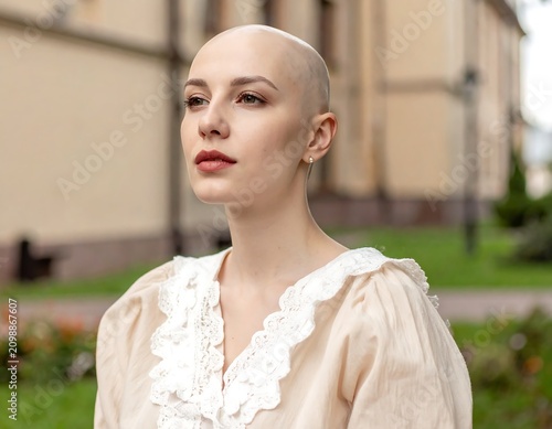 Woman with shaved head, wearing vintage blouse