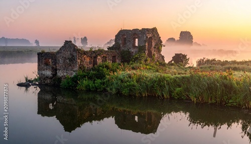 Ancient stone castle ruins at golden hour by serene lake.