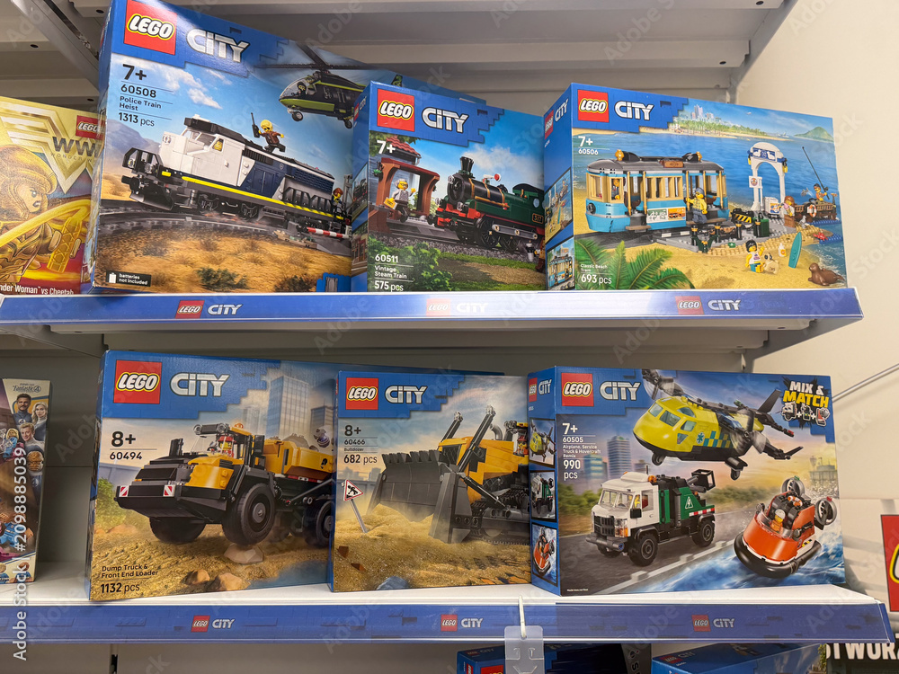 Fototapeta premium Toy store shelf filled with lego city building sets and vehicle boxes on display