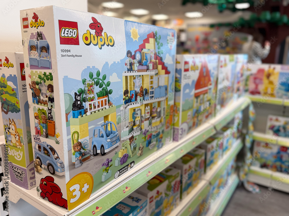 Fototapeta premium Row of lego duplo toy boxes on a store shelf in a colorful toy aisle, showing building sets for young children