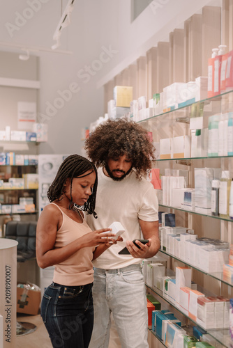 Young couple checking medication information on smartphone in pharmacy