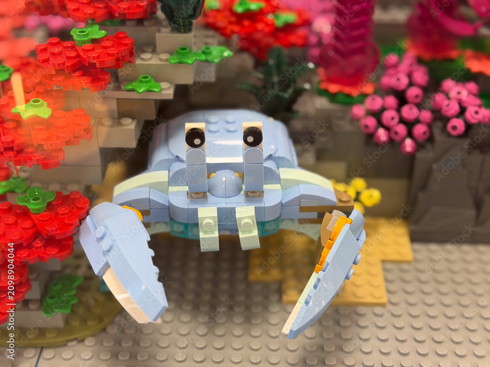 Fototapeta premium Colorful lego crab figure displayed in a playful garden scene with bright flowers and blocks, creative toy build for kids and collectors