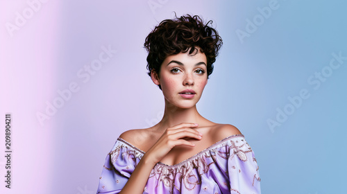 Woman in Off-Shoulder Top Against Pastel Background.