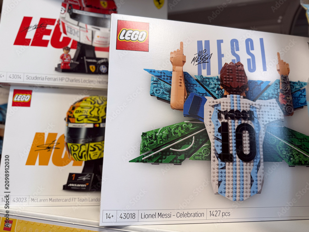 Fototapeta premium Lego toy boxes on a store shelf, including lionel messi celebration set and formula 1 race car packs, displayed in a retail aisle.