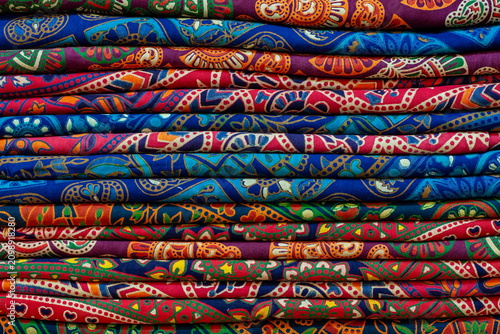 Brightly colored textile fabrics stacked together. Beautiful traditional oriental and Indian bohemian patterns on cotton material. Perfect for fashion retail, interior decor and textile design