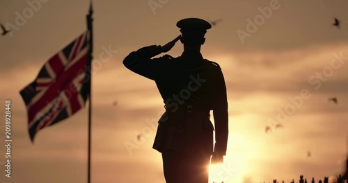 Silhouette of a soldier saluting at sunset with a British flag in the background.