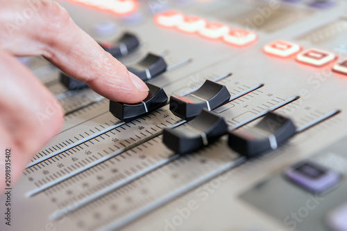 Foto Close up of hand adjusting fader on sound mixing console in studio
