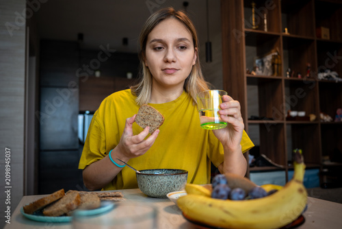 Woman holding a slice of whole-grain bread and a glass of water for a healthy breakfast. Mindful eating, morning nutrition, and wellness routine.