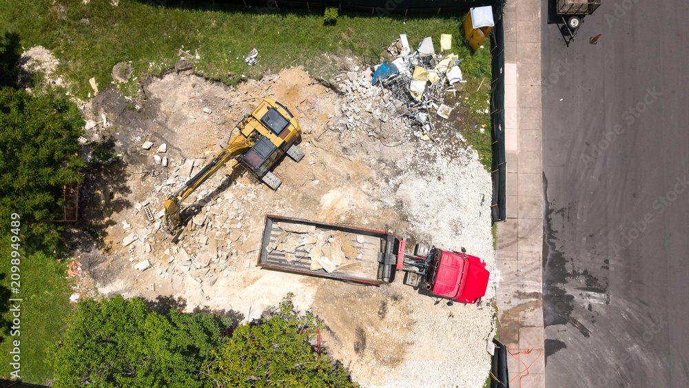 Obraz premium Aerial view of an excavator loading construction debris into a dump truck