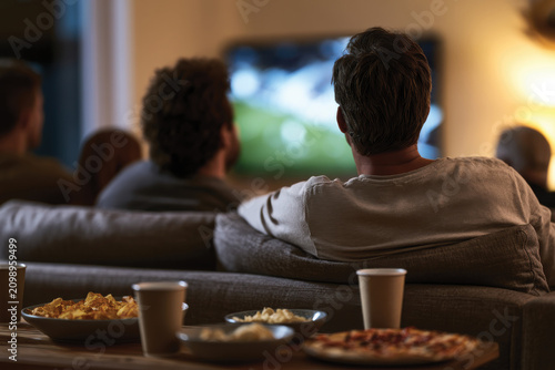 A group of friends enjoy an engaging movie night at home, with bowls of popcorn and pizza, creating a warm and inviting atmosphere for connection and laughter.