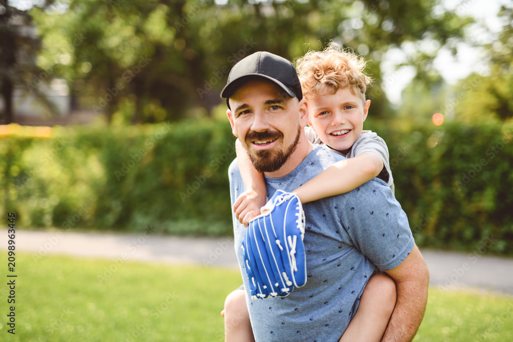 Fototapeta premium Father and son playing baseball in sunny day at public park
