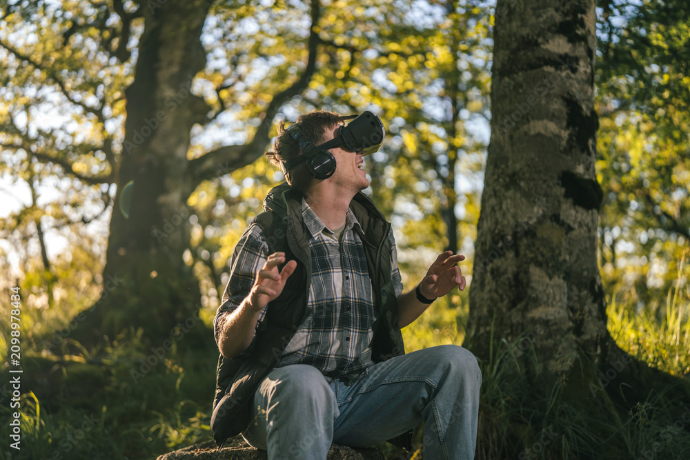 Obraz premium Man experiencing virtual reality outdoors in forest