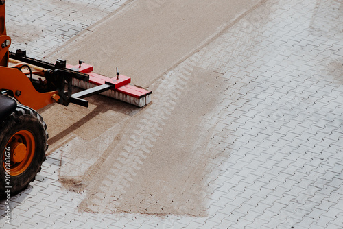 Worker sweeping sand into paver joints during patio installation