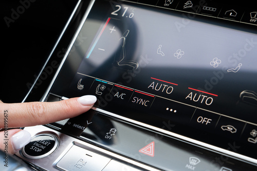 Photography Woman finger pressing ventilated seat button on luxury car touch screen