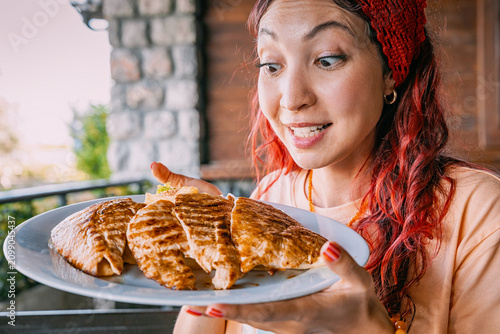 Принти на полотні Young woman with red hair showing excitement while holding a plate of grilled ch