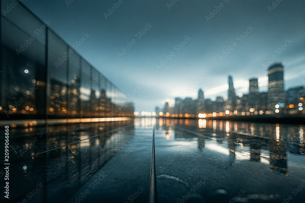 Fototapeta premium A moody, low-light cityscape reflection on a wet street under an overcast sky.