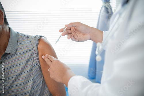 Foto A male healthcare worker wearing gloves safely administers a vaccine to promote disease prevention, well-being, research, and attentive patient care in a clinical setting