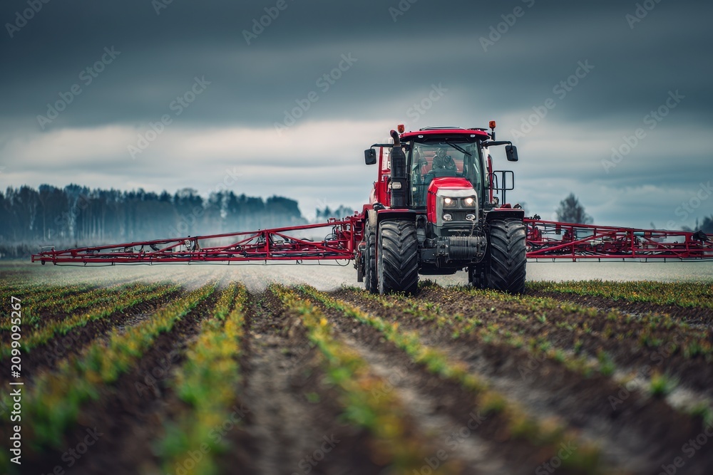 Obraz premium Wide-field view of a spraying vehicle applying fertilizer in spring amid gray clouds