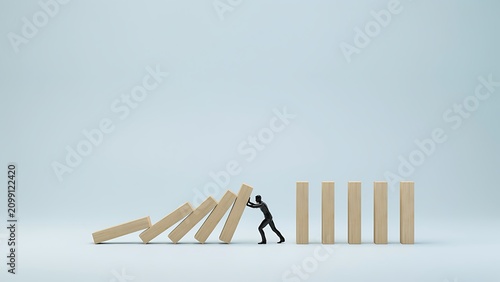 A person stops a domino effect by pushing a block, preventing a chain reaction.