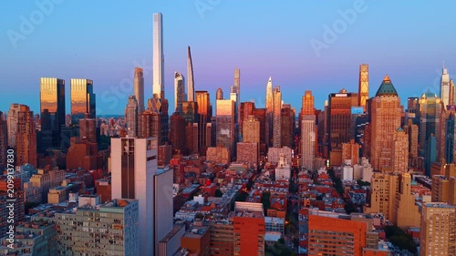 Midtown Manhattan skyline under clear evening sky. Skyscrapers and residential blocks reflect warm sunset light in New York City.